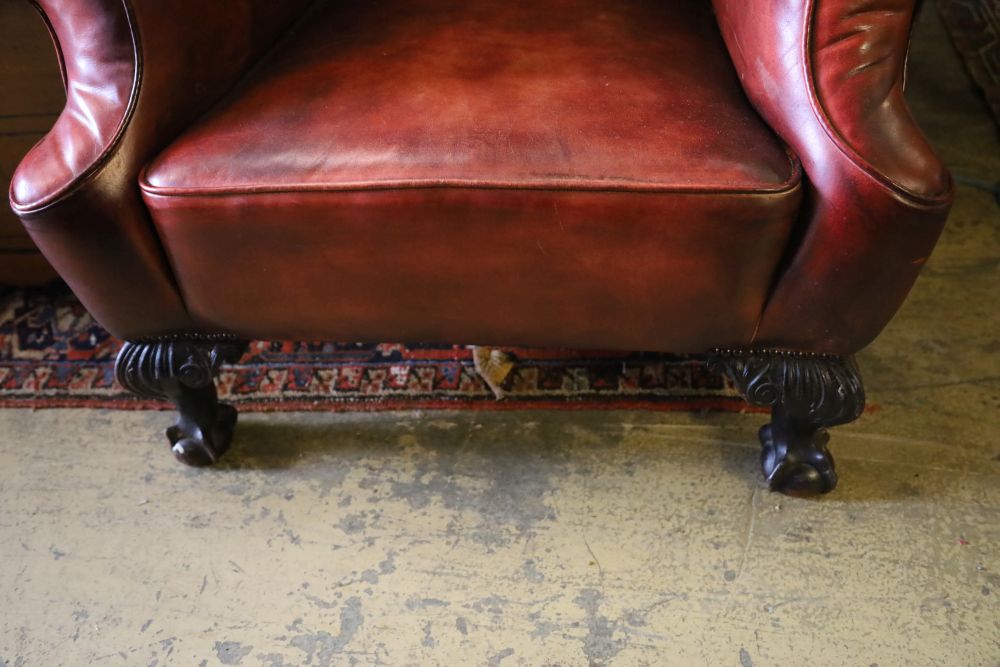 An early 20th century wing back armchair upholstered in burgundy leather on carved claw and ball feet, width 80cm, depth 82cm, height 1